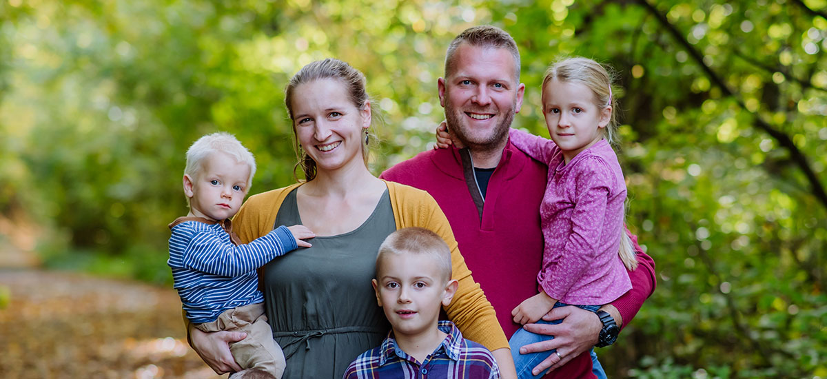 Junge Eltern mit drei kleinen Kindern im Wald